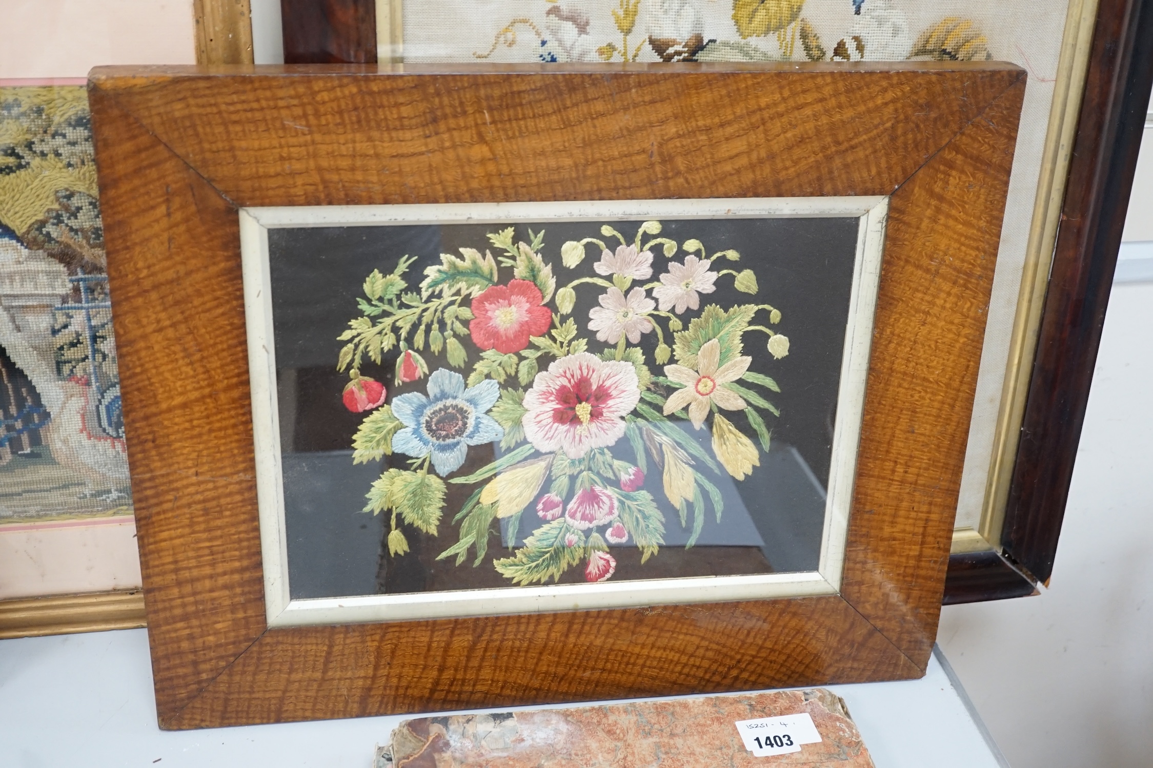 19th century and later framed embroideries (5); a 19th century wool worked still life embroidery, a later similar silk embroidery, a figurative wool worked embroidery, silk embroidery of a galleon and a landscaped wool w
